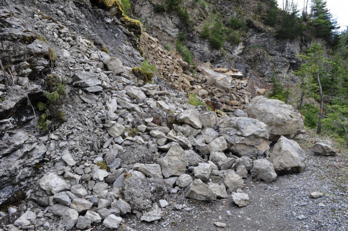 Ein heruntergerutschter Geröllhaufen versperrt eine Schotter-Alpstrasse.