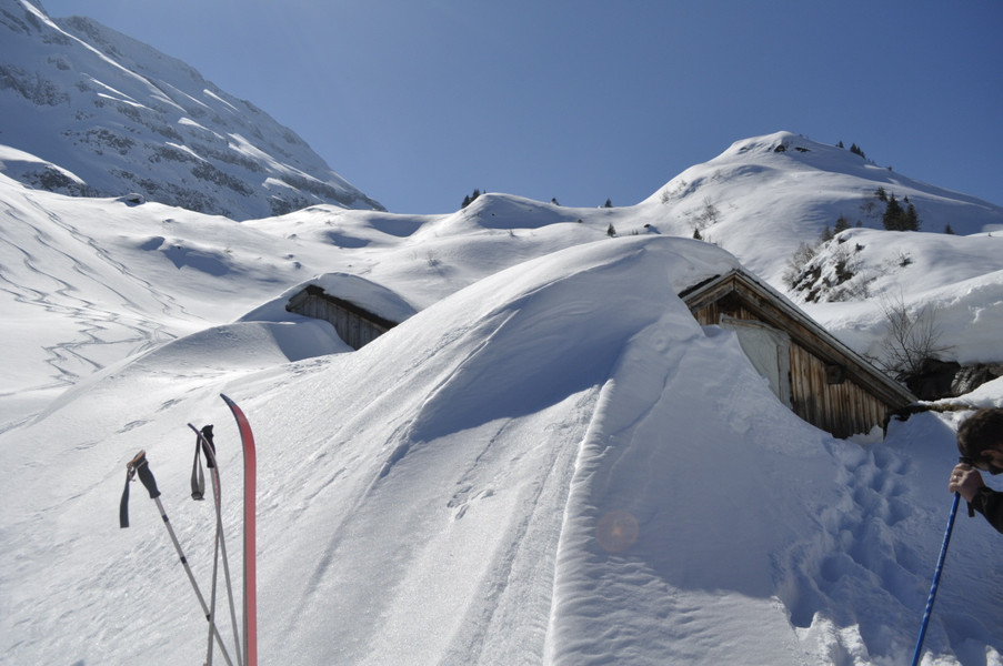 die alte Hinderist Hütte tief eingeschneit; man sieht nur den Giebel der Hütte und auch des Stalles daneben