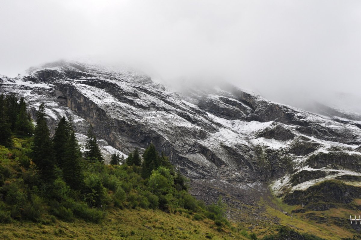Die First ist 'überguslät'. Die Weiden untendran sind schneefrei. Der oberste Teil der First ist in weissen Wolken.